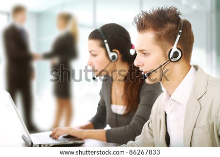 Customer service representatives in modern office with  headsets. Business people shaking hands on background