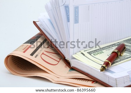 Newspaper, pen and notebook with cash on blue background