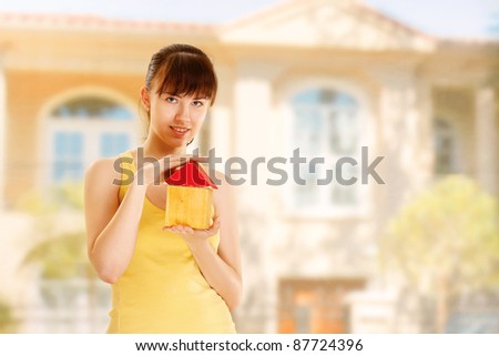 Young woman with toy house isolated on white background