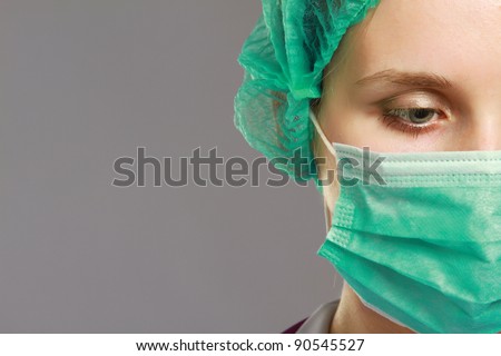 A female doctor wearing a mask, isolated on grey background