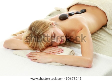 Relaxed young woman getting hot stone message at spa salon isolated on white