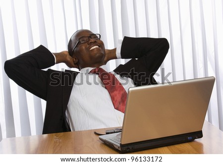 Portrait of an African American sitting on the desk with laptop