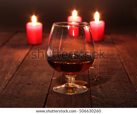 Christmas Composition with glass cognac, Gift box and candle on wooden table.