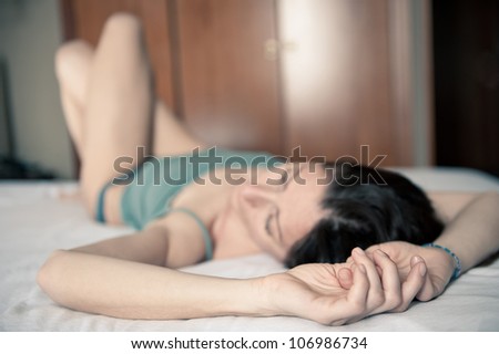 Portrait of a sensual woman lying on bed in hotel room. Shallow depth of field.