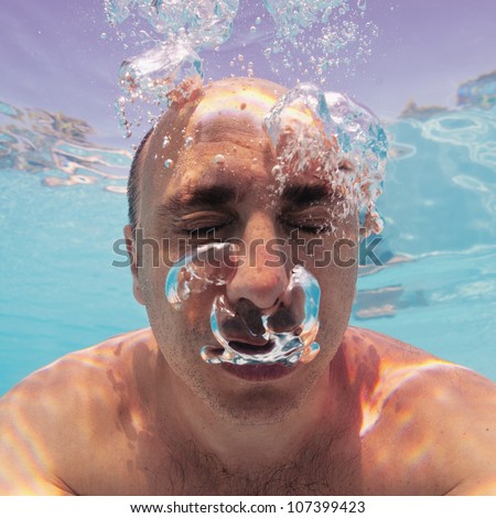 Underwater portrait of bald man with bubbles in a swimming pool.