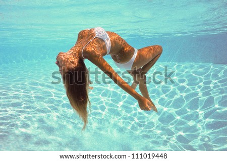 Underwater woman portrait with white bikini in swimming pool.
