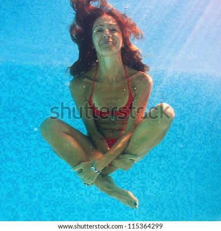 Smiling woman underwater close up portrait in swimming pool.