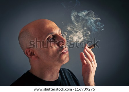 Bald man smoking cigar portrait on dark background.