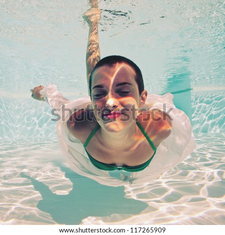 Underwater woman portrait with green bikini in swimming pool.