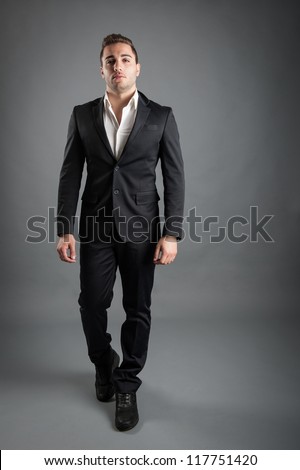 Young man full body portrait against grey background.