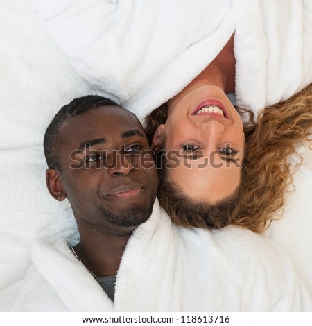 Happy young couple lying in bed, top view.