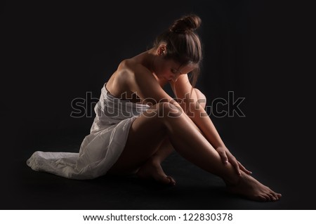 Intimate woman portrait wearing white dress against dark background.