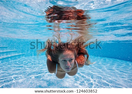 Close up portrait of underwater woman in swimming pool.