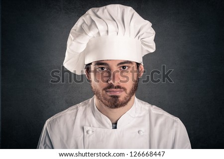 Young cook man wearing uniform close up portrait over grunge background.