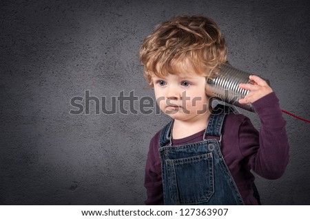 Young kid listen to tin can telephone over grunge background.