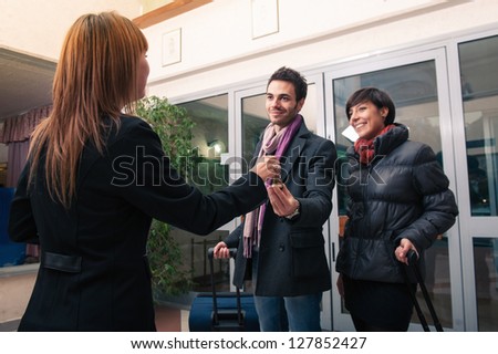 Happy young couple entering in hotel with key of the room. Focus on key.