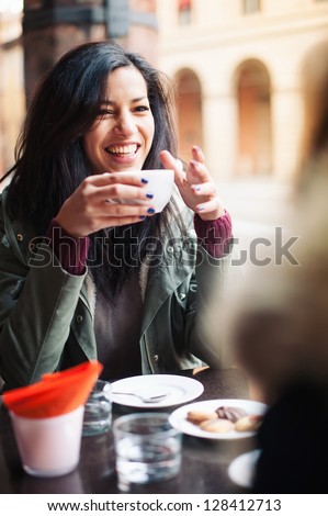 Young woman drinking coffee in a cafe outdoors. Shallow depth of field.