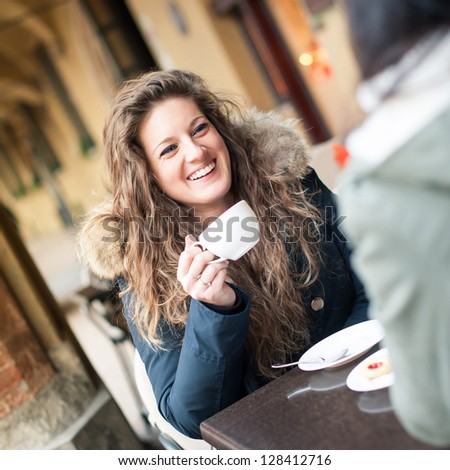 Young Woman Drinking Coffee With Friend In A Cafe Outdoors. Shallow Depth Of Field.