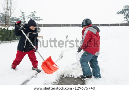 Young kids shoveling snow off sidewalk.