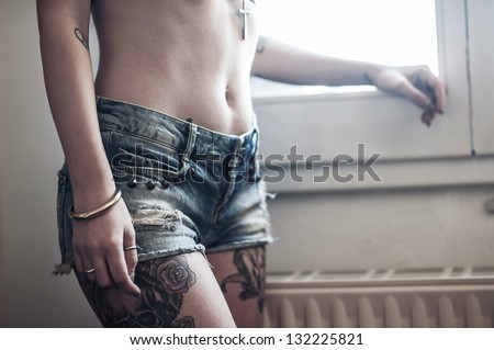 Close up of beautiful girl with tattoo wearing jeans short paint.