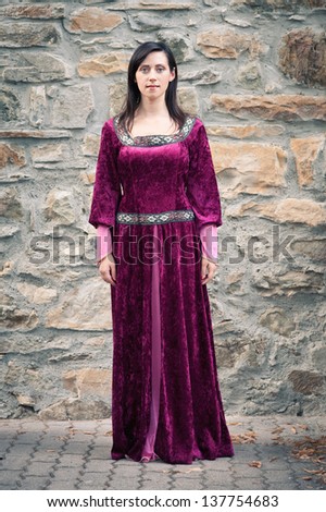 Beautiful girl wearing a burgundy medieval dress. Full body portrait.