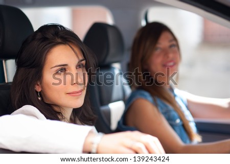 Two young female friends in a car leaving for vacation.