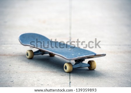 Old used skateboard isolated on the ground. Shallow depth of field.