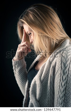 Blonde woman close up profile portrait on dark background.