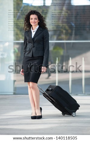 Business woman portrait outdoors walking with trolley. Full body.