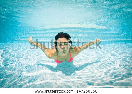 Girl portrait underwater with pink bikini in swimming pool.