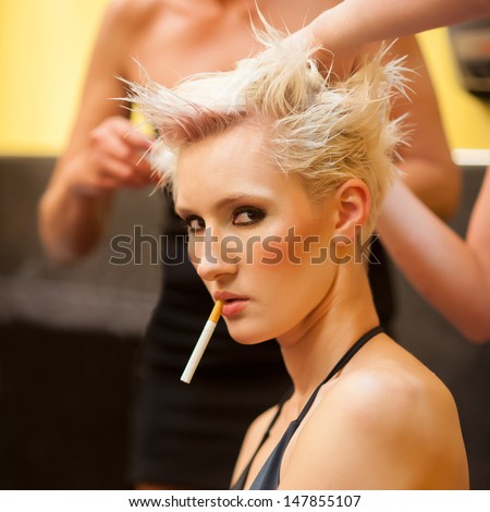 Sexy woman smoking cigarette while making hair style.