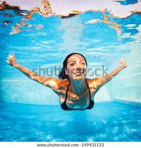 Underwater woman portrait wearing black bikini in swimming pool.