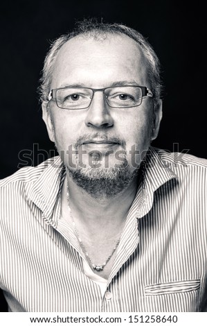 Middle age man close up portrait against black background. Black and white image.