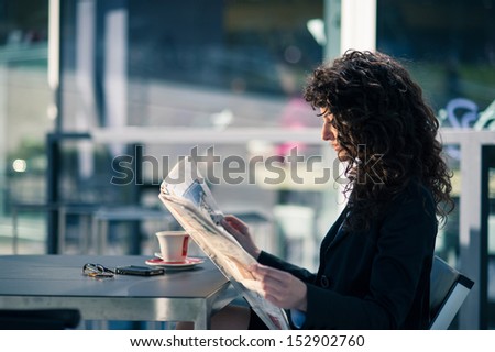Business Woman Reading Newspaper Outdoors Sit In A Bar. Shallow Depth Of Field.