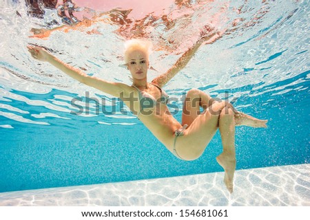 Beautiful woman full body portrait underwater in swimming pool.