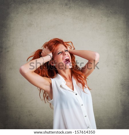 Screaming redhead woman portrait against grunge background.