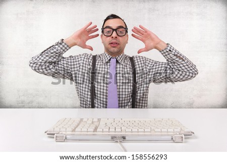Computer geek surprised while looking at computer isolated on grunge background