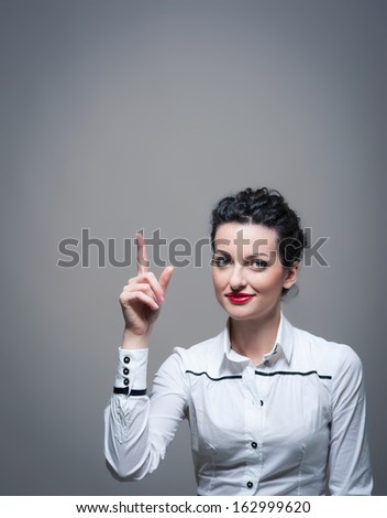 Business woman with finger pointing isolated against dark background with copy space.