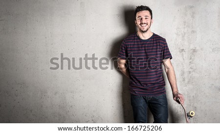 Laughing Skateboarder Portrait Standing Against Concrete Wall.