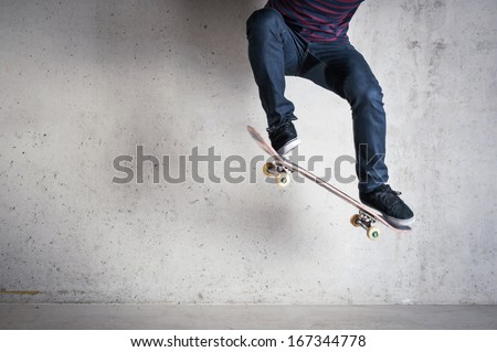Skateboarder doing a skateboard trick - ollie - against concrete wall.