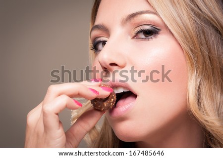 Close up of beautiful blonde woman eating chocolate.