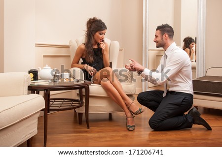 Young man making a marriage proposal to his girlfriend in hotel.