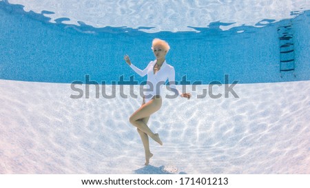 Beautiful woman full body fashion portrait underwater in swimming pool.