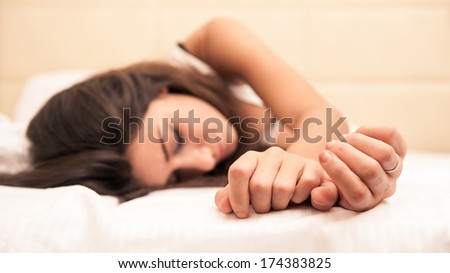 Sensual young woman portrait while sleeping on bed in hotel room. Shallow depth of field.