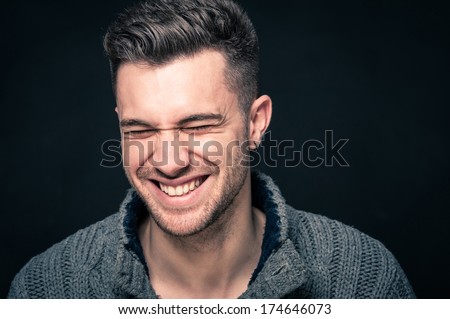 Laughing man close up portrait against dark background.