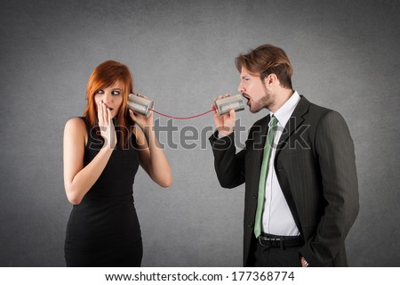 Couple discussing with tin can telephone against grunge background.