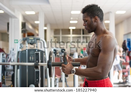 Strong black man adjusting heavy lift on bar in the gym.