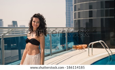 Young woman portrait wearing bikini sunbathing in swimming pool in Dubai. Filtered image