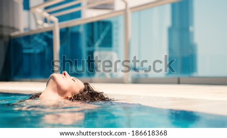 Young woman portrait wearing bikini sunbathing in swimming pool in Dubai. Filtered image.