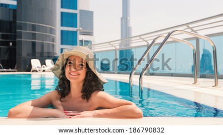 Happy woman portrait wearing bikini sunbathing in swimming pool in Dubai. Filtered image.